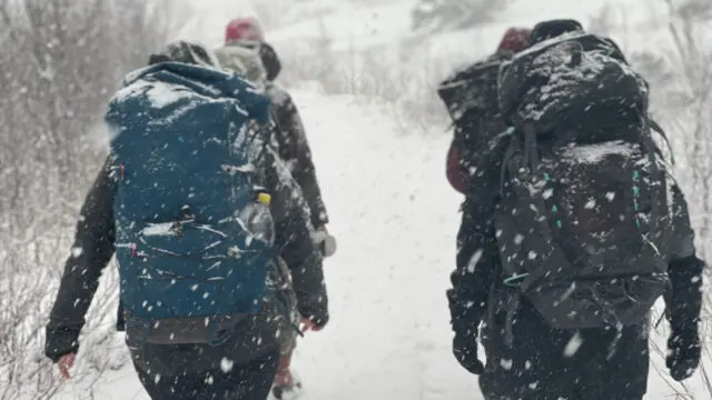 Vandrare med ryggsäckar på väg i snöyra